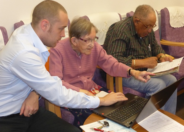 An image showing digital champions helping a resident set up her laptop