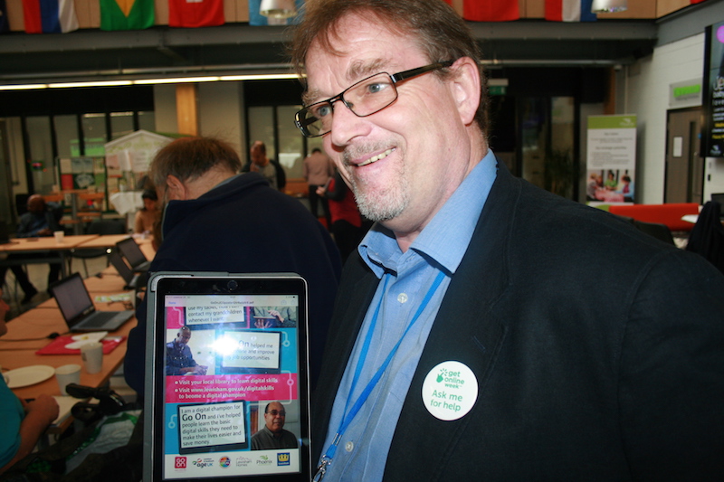 A photo showing digital champion and Go ON Lewisham coordinator, Liam Barnes, showing a promotional flyer