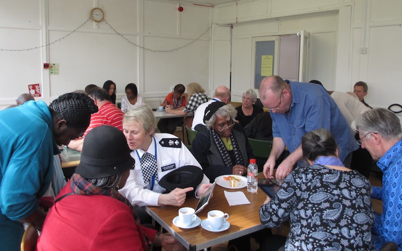 A photo showing the police borough commander helping at a techy tea party for senior residents